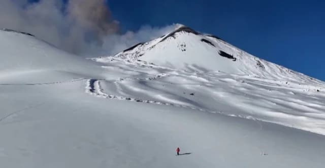 Ätna bricht aus, während Skifahrer die Hänge hinabfahren